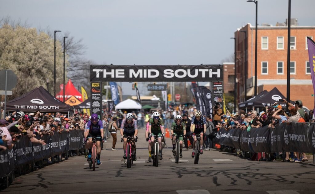 Ten cyclists start the MidSouth 2026 Non-Binary Pro race with the finish line visible in the background.